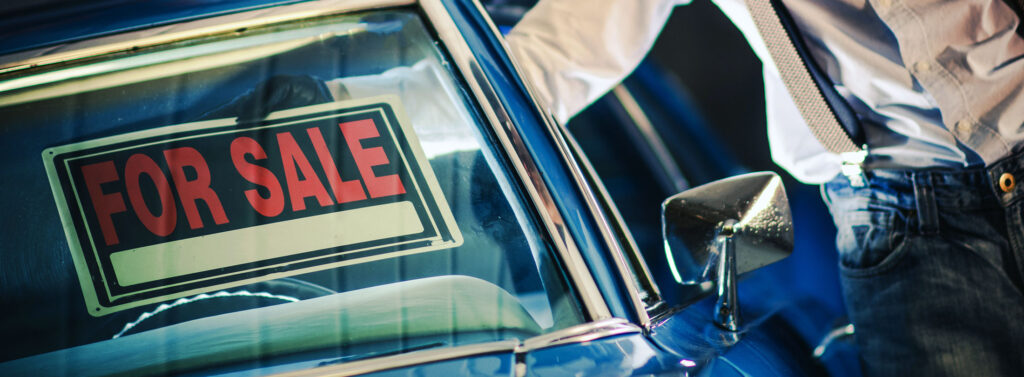 How to Sell & Market a Used Car. Man is shown putting a for sale sign in the windshield.