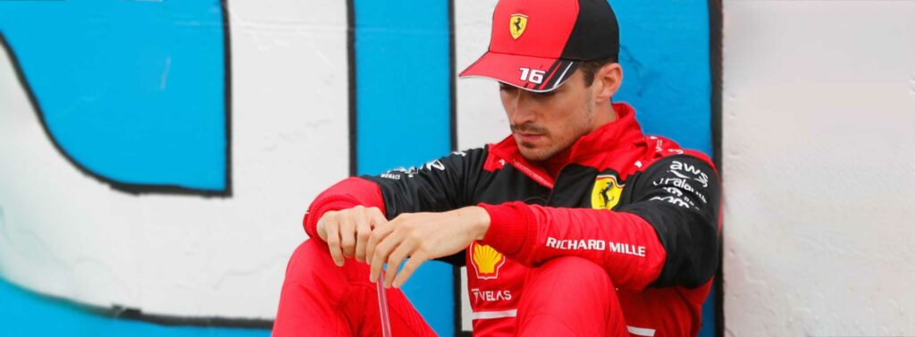 Ferrari F1 driver Charles LeClerc sitting track side on the grid.