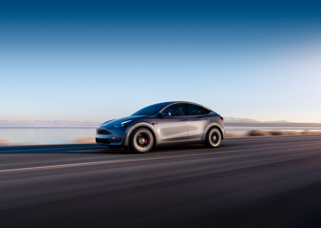 Image showcasing driver front quarter profile of the Tesla Model Y on highway near