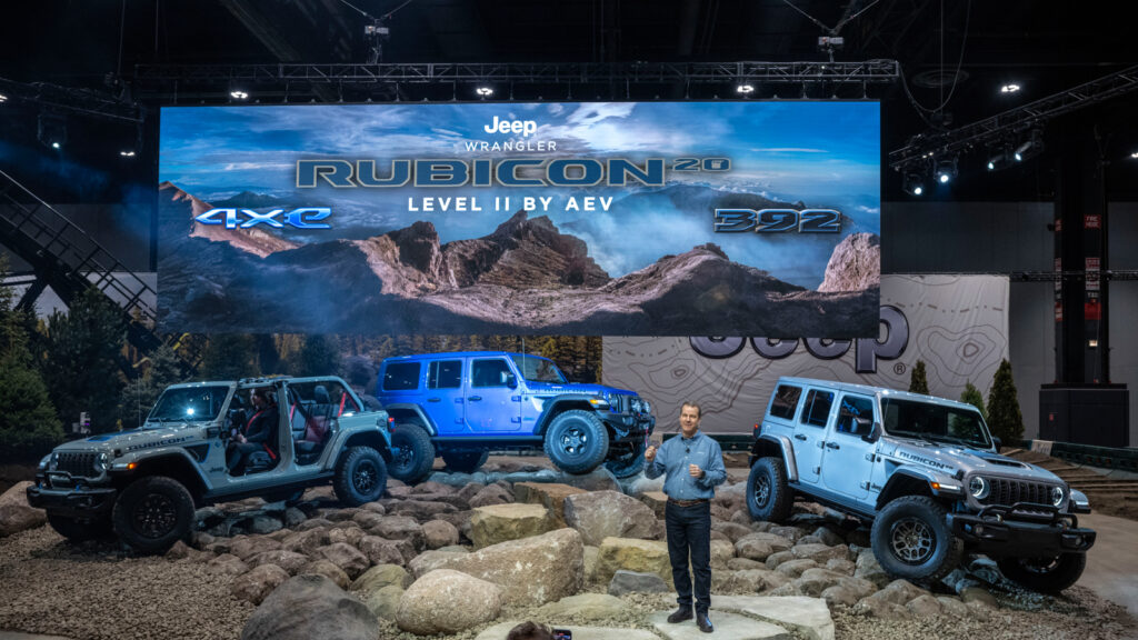 Image showcasing Jim Morrison, senior vice president and head of Jeep brand – North America, reveals Rubicon 20th Anniversary editions of the 2023 Jeep Wrangler 4xe, left, and Wrangler 392, right, as well as the Rubicon 20th Anniversary Level II upfit by American Expedition Vehicles (AEV), center, which features 37-inch tires, at the 2023 Chicago Auto Show.